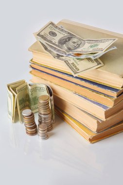 Finansal eğitim kavramı - para: faturalar, sikkeler, cam bir masa üzerinde eski kitaplar. 