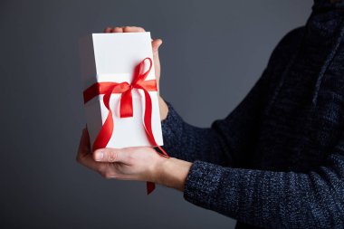  Erkek elinde kırmızı kurdele ile beyaz hediye kutusu. Yumuşak odak