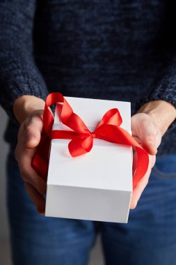  Erkek elinde kırmızı kurdele ile beyaz hediye kutusu. Yumuşak odak