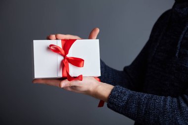  Erkek elinde kırmızı kurdele ile beyaz hediye kutusu. Yumuşak odak