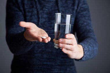 Erkek su hap çözülmeye hazır. Çözünür beyaz hap ve bir bardak su onun elinde. Efervesan tablet aspirin bardak su