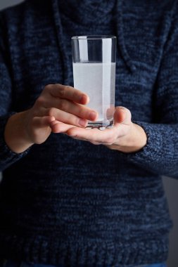 Bir bardak tutan erkek Doğum kontrol hapı suda çözünmüş. Çözünür beyaz hap ve bir bardak su onun elinde. Efervesan tablet aspirin bardak su