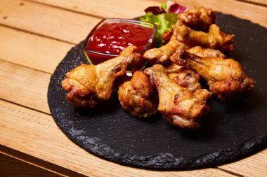 Bir kara tahta ahşap arka plan üzerinde ızgara tavuk budu (sopaları). Ketçap ve salata ile servis. Metin, kopya alanı için yer