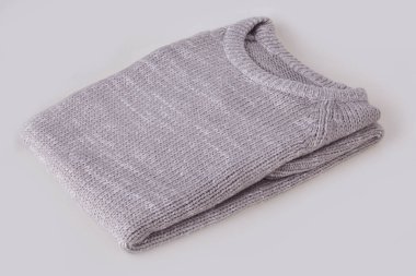 Gri, beyaz arka plan üzerinde boş etiketi ile örme kazak katlanmış. Giyim, moda kavramı. Uzun kollu tunik