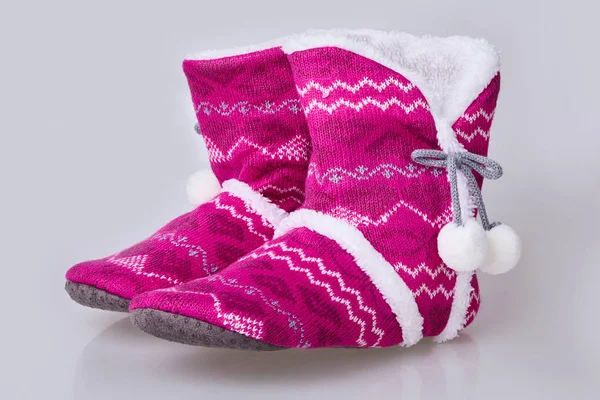 Pink knitted slippers on a white background. Soft warm comfortable home slippers