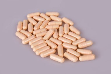 Spilled beige capsules on the white background. Vitamin supplements tablets