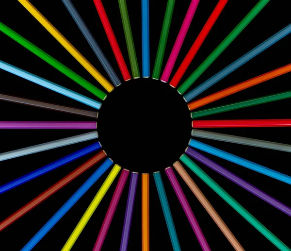 Set of color pencils in circle close together on black background top view