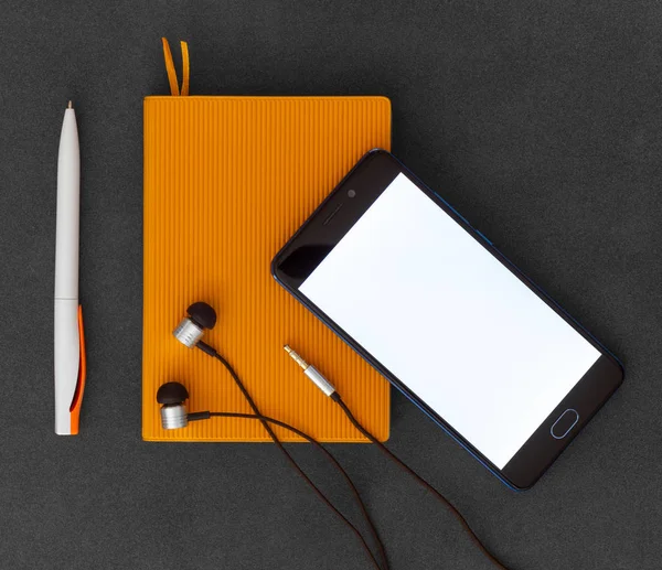 橙色纸笔记本 笔和耳机 位于深色背景顶视图上 — 图库照片