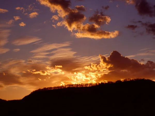 Ormanla kaplı karanlık tepenin üzerinde güzel gün batımı. 
