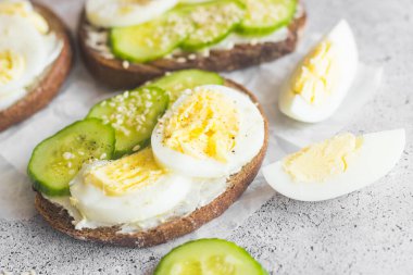 Yumurtalı sandviç, salatalık, susam tohumu ve baharat. Lezzetli bir kahvaltı. Sandviçler masada.