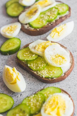 Yumurtalı sandviç, salatalık, susam tohumu ve baharat. Lezzetli bir kahvaltı. Sandviçler masada.