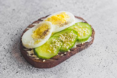 Yumurtalı sandviç, salatalık, susam tohumu ve baharat. Lezzetli bir kahvaltı. Sandviçler masada.
