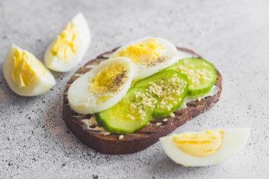 Yumurtalı sandviç, salatalık, susam tohumu ve baharat. Lezzetli bir kahvaltı. Sandviçler masada.