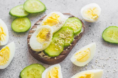 Yumurtalı sandviç, salatalık, susam tohumu ve baharat. Lezzetli bir kahvaltı. Sandviçler masada.