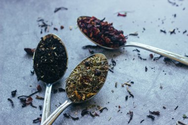 Kaşıklar içinde çeşitli bitki çayları. Çay yapraklı kaşıklar. Beton zeminde çay