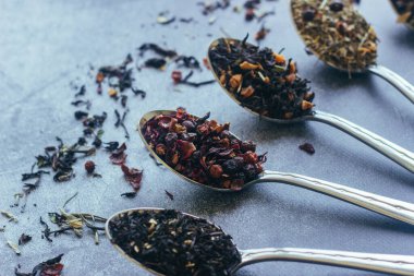 Kaşıklar içinde çeşitli bitki çayları. Çay yapraklı kaşıklar. Beton zeminde çay