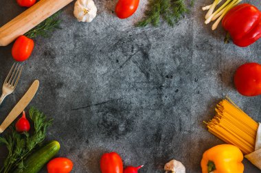 Beton zeminde sebzeler. Domates, salatalık, biber, turp, sarımsak, soğan, çimento bir masada otlar.