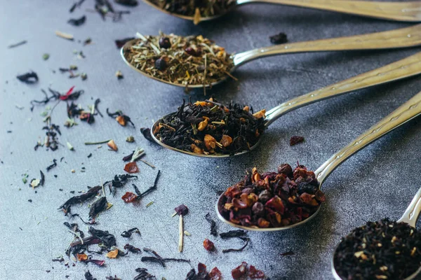 Kaşıklar içinde çeşitli bitki çayları. Çay yapraklı kaşıklar. Beton zeminde çay