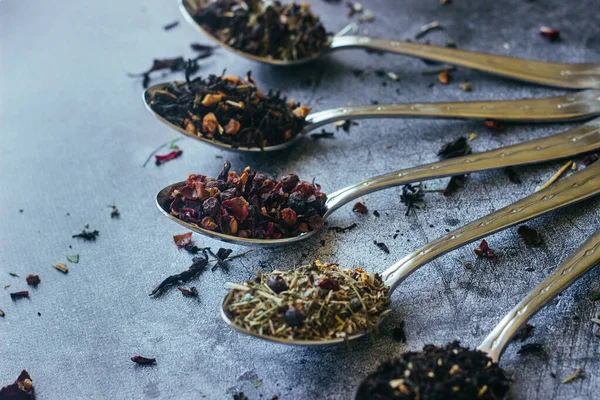 Kaşıklar içinde çeşitli bitki çayları. Çay yapraklı kaşıklar. Beton zeminde çay