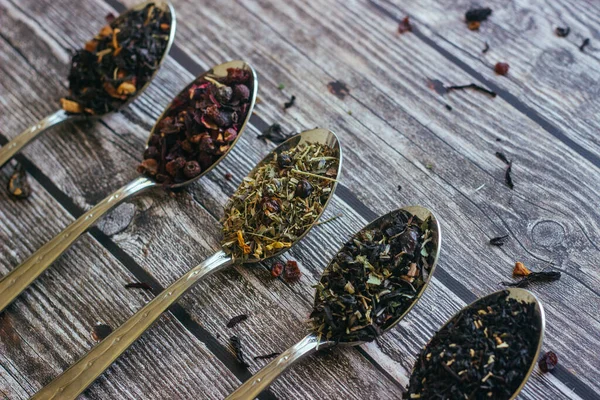 スプーンでハーブティーの様々なタイプ 乾燥茶葉を持つスプーン 木の背景に茶 — ストック写真