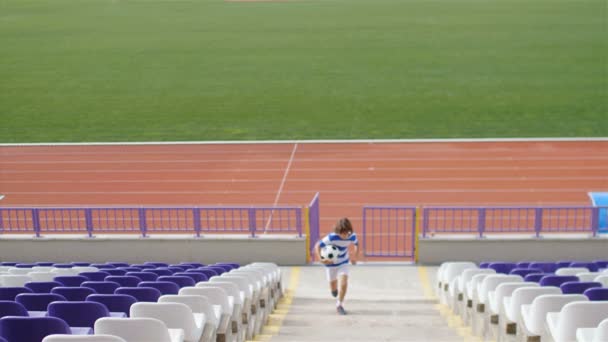 Медленное Движение Юного Футболиста Футбольным Мячом Бегущим Среди Трибун Стадиона — стоковое видео