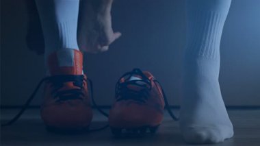 Futbol futbol oyuncusu onun ayakkabıları koymak. Ağır çekim. 
