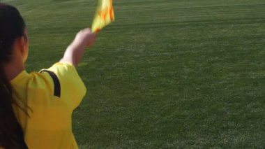 Asistan kadın hakem bir futbol maçı sırasında kenarda hareket ediyor.