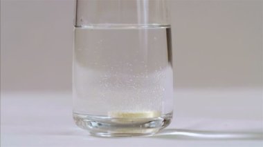 Şişirilmiş C vitamini tableti siyah arkaplanda bir bardak suda köpürüyor, 75 fps yavaş çekim