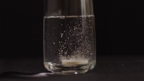 发泡的维生素C片泡沫在一杯黑色背景的水中 Fps慢动作 — 图库视频影像