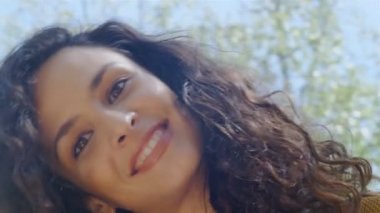 Güzel kıvırcık saçlı mutlu bir genç kadının portresi. Döner döner atlı karınca, 75 fps yavaş çekim.