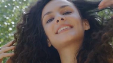 Güzel kıvırcık saçlı, neşeli, mutlu bir genç kadının portresi.