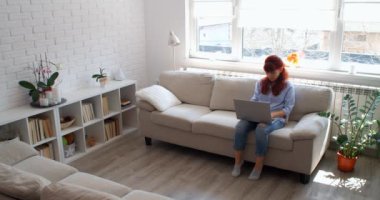 Ev kavramından çalış. İş kadını serbest çalışan, ev bilgisayarında e-posta yazan, bilgisayar kullanan, kanepeye oturan, internet işiyle meşgul bir kadın, 4K