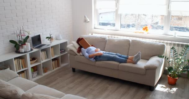 Covid 19の間は家にいてください 女はソファの上に横たわり遠隔操作でテレビを見て — ストック動画