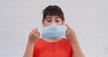 COVID-19 sağlık konsepti. Beyaz kız evde koruyucu bir tıbbi maske takıyor. 4k
