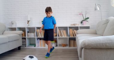 6 yaşında bir çocuk COVID-19 karantinası sırasında evde futbol oynuyor. Dairesinde hayat devam ediyor. 4k