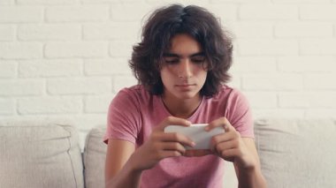 4K Genç çocuk evde telefonundan bir şey izlerken pozitif tepki gösteriyor.