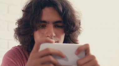 4K Genç çocuk evde telefonundan bir şey izlerken pozitif tepki gösteriyor.