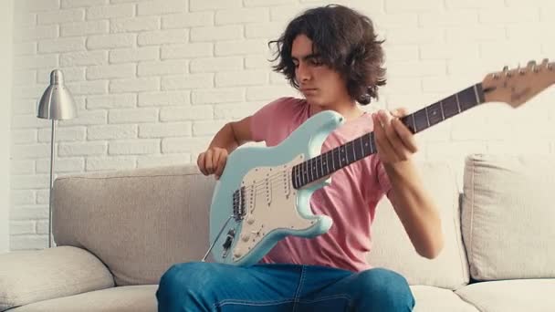 十几岁的男孩正坐在家里的床上弹着吉他 — 图库视频影像