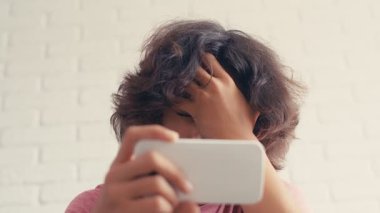 4K Genç çocuk evde telefonundan bir şey izlerken olumsuz tepki gösteriyor.