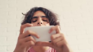 4K Genç çocuk evde telefonundan bir şey izlerken pozitif tepki gösteriyor.