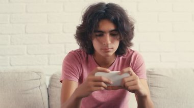 4K Genç çocuk evde telefonundan bir şey izlerken pozitif tepki gösteriyor.