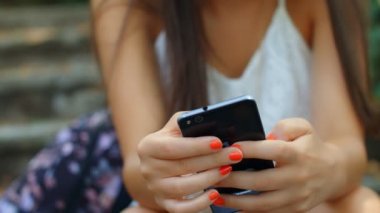 Parkta akıllı telefon kullanan güzel bir kadının portresi, 4K.