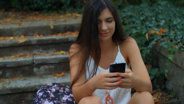 Πορτρέτο Μιας Όμορφης Νεαρής Γυναίκας Που Χρησιμοποιεί Smartphone Στο Πάρκο — Αρχείο Βίντεο