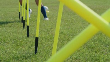 Futbol çeviklik eğitim ekipmanları. Çevik direkleri olan profesyonel futbolcu genç bayan oyuncu. 4k ağır çekim