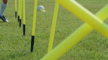 Futbol çeviklik eğitim ekipmanları. Çeviklik çubukları olan genç bir futbolcunun bacaklarının detaylı görüntüsü. 4k ağır çekim