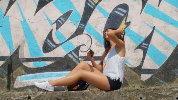 Csinos Fiatal Csinál Egy Szelfit Egy Okostelefonnal Fal Grafitokkal Háttérben — Stock videók