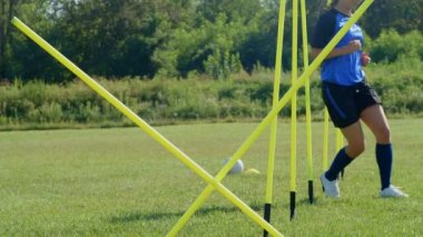 Futbol çeviklik eğitim ekipmanları. Çevik direkleri olan profesyonel futbolcu genç bayan oyuncu. 4k