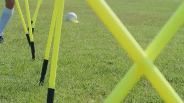 Futbol çeviklik eğitim ekipmanları. Çeviklik çubukları olan genç bir futbolcunun bacaklarının detaylı görüntüsü. 4k ağır çekim