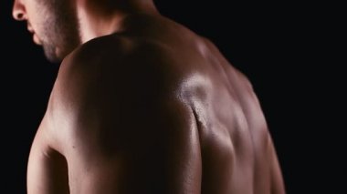 Daha büyük kaslar için halterleri kaldırıyorum. Büyük pazıları olan yakışıklı bir adam karanlık arka planda ağırlık kaldırıyor. 4k