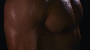 Daha büyük kaslar için halterleri kaldırıyorum. Büyük pazıları olan yakışıklı bir adam karanlık arka planda ağırlık kaldırıyor. 4k